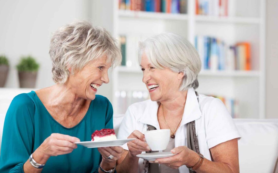 two elderly ladies laughing over a cup of coffee